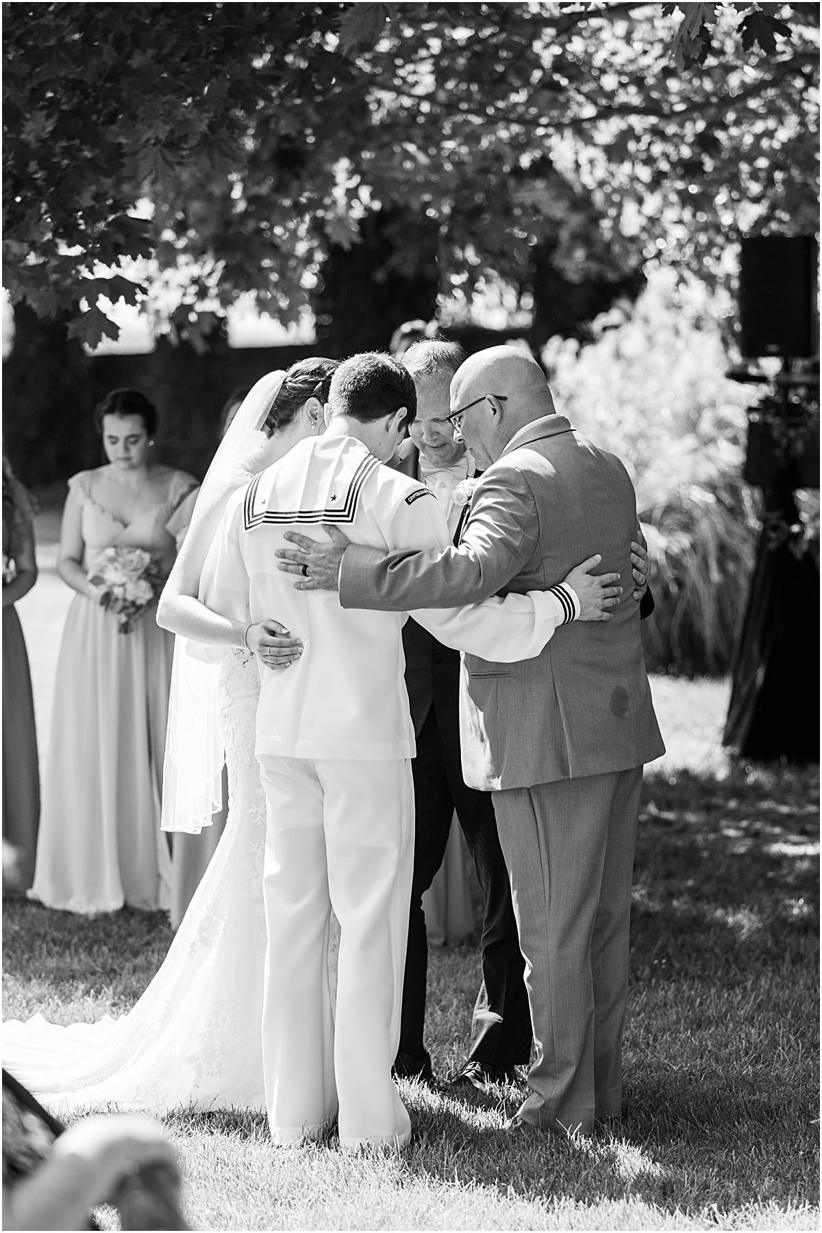 Black and white photo of the bride, groom, and their fathers praying during the ceremony. Wedding photography in Maryland done by Ashley.