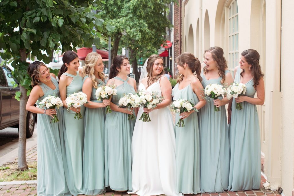 Jessica posing with all of her bridesmaids, on a city sidewalk, wedding photography done in Alexandria Virginia
