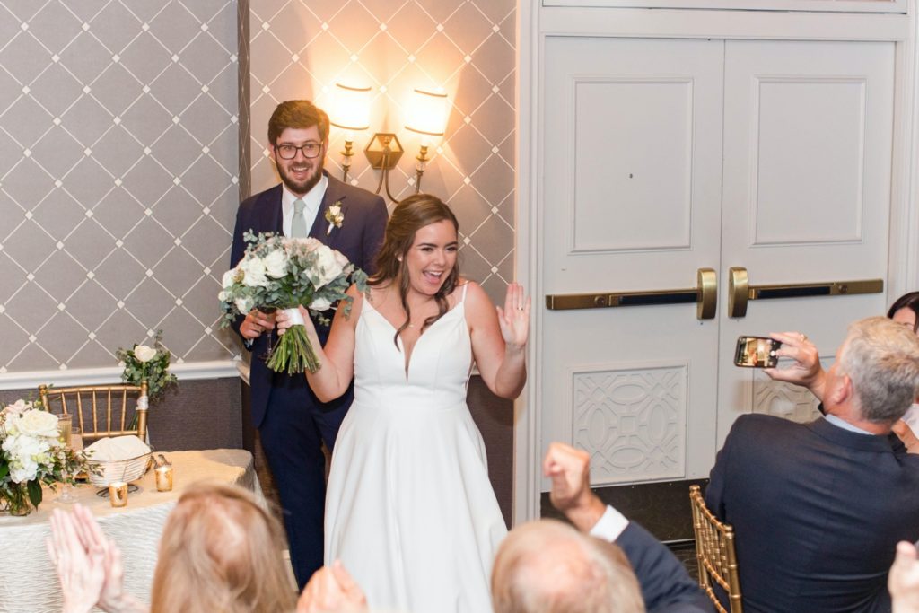 The new couple walk into the reception hall to cheers and clapping, wedding photography done in Alexandria Virginia.