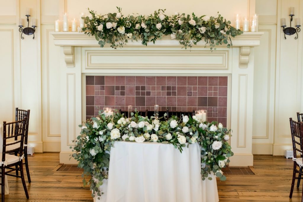 reception detail photo of bride and groom table with white linens and white and green florals
