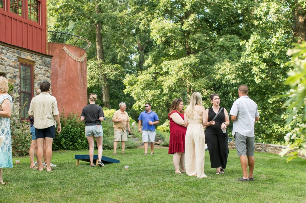 Couples, friends and family mingling while playing lawn games at the rehearsal dinner photography session.