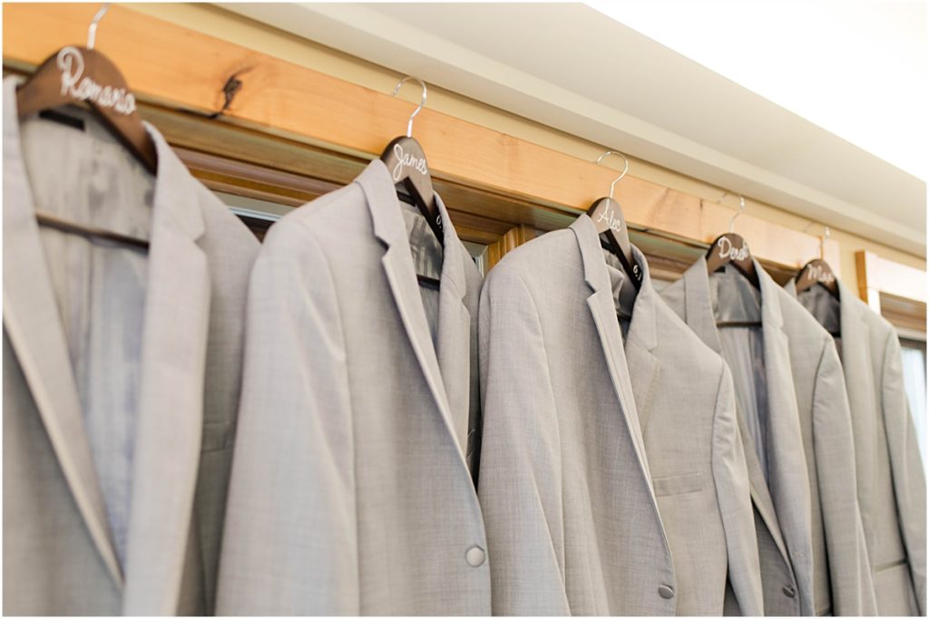 The groom and groomsmen's suits hanging in a window.