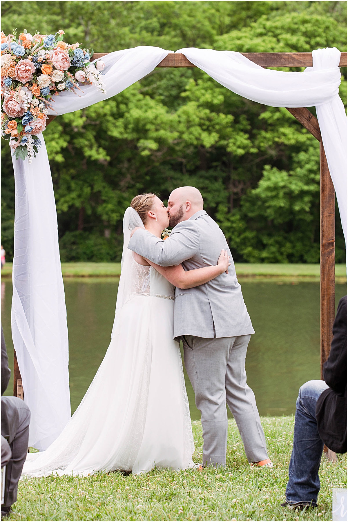 Anneliese and Alec share their first kiss as husband and wife in front of the pond at Poor Farm House Park.