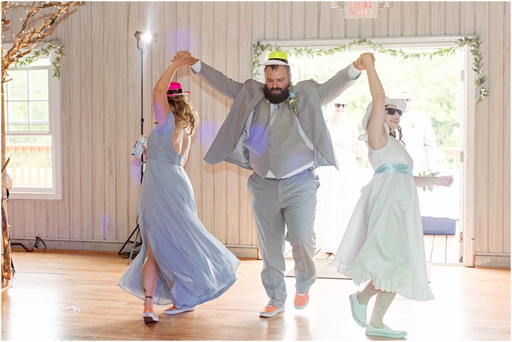 A groomsmen spinning two of the bridesmaids as they enter the wedding reception at Poor Farm House Park.