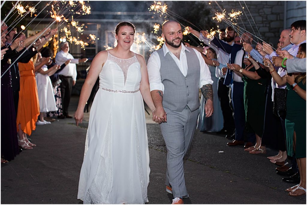 Alec and Anneliese walking through a tunnel of sparkler during their wedding day exit at Poor Farm House Run.
