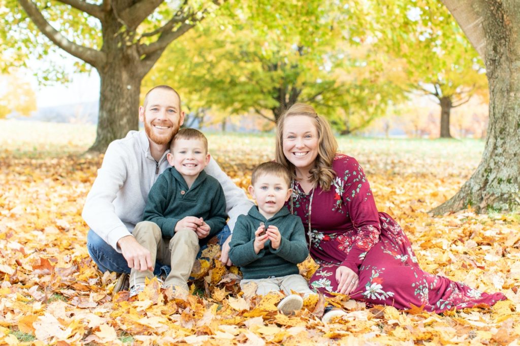 A family taking Fall portraits among the leaves.